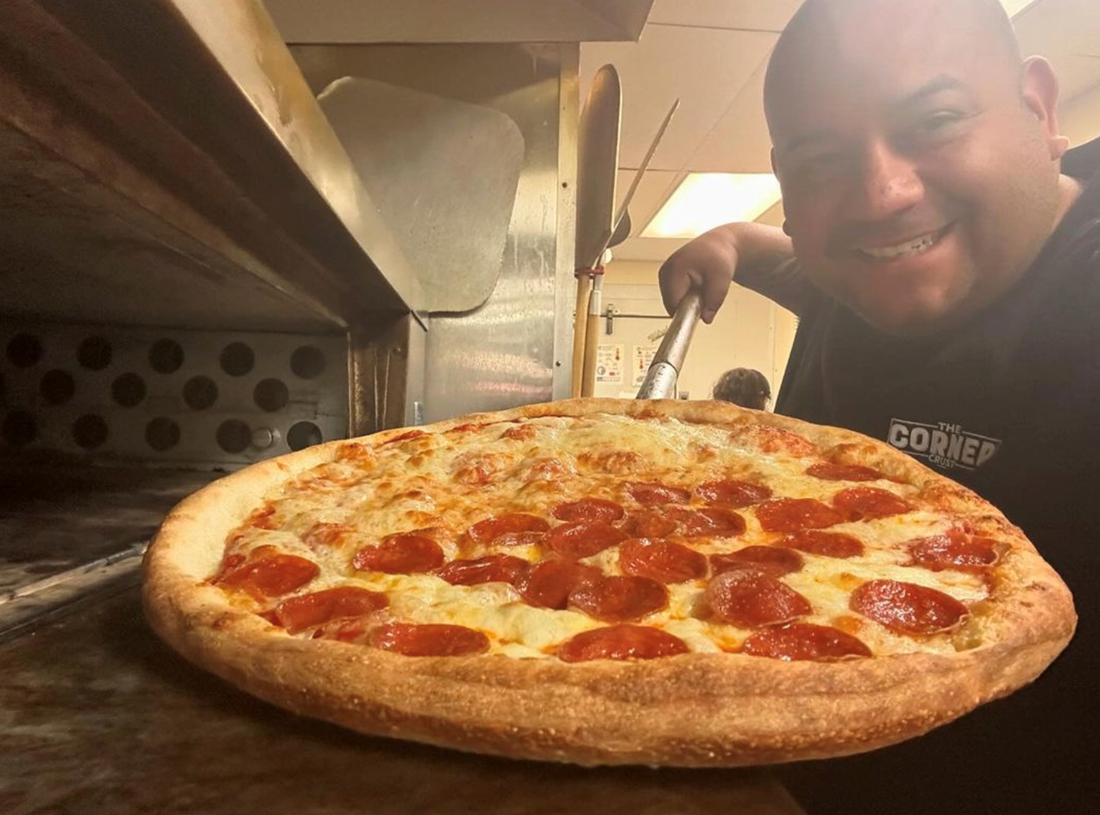 Employee at Big City Slices working the pizza oven